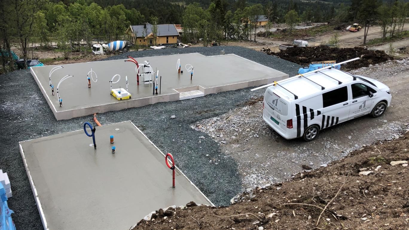 Nystøpte betongplater med oppstikk for vann og avløp, klare for videre bygging i naturskjønne omgivelser.