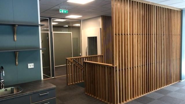 Kontorlokaler med kjøkkenkrok og spilevegger som skaper en lun og strukturert romfølelse.